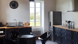 A compact kitchen with a window, a clock, and modern appliances. - 19th Century family home with terrace & garden, ideal for 10 people. (Cindré)