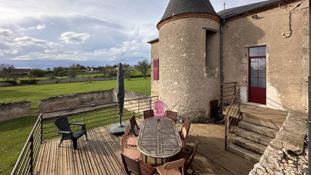 A rustic outdoor patio with a round table and chairs, a stone tower, and a view of the countryside. - 19th Century family home with terrace & garden, ideal for 10 people. (Cindré)
