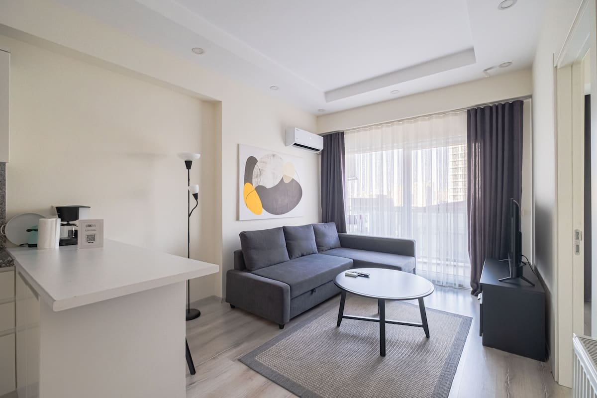 A modern living room with a grey sofa, a white coffee table, and a flat-screen TV.
