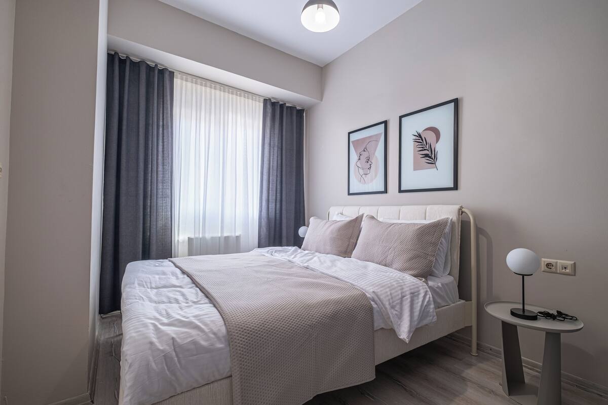 A modern bedroom with a bed, a bedside table, and two framed artworks on the wall.