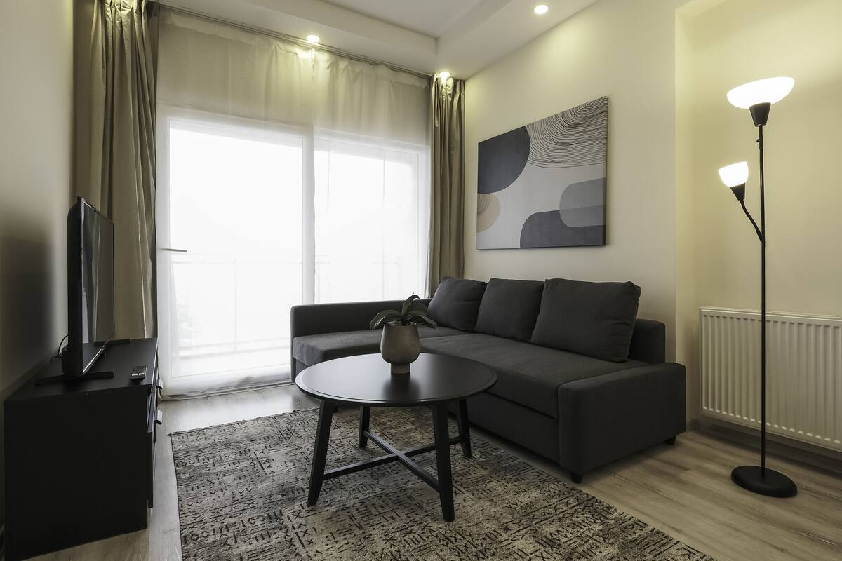 A modern living room with a sofa, a coffee table, a TV, and a floor lamp.