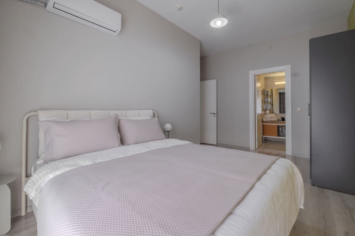 A bedroom with a large bed, a wardrobe, and a door leading to a bathroom.