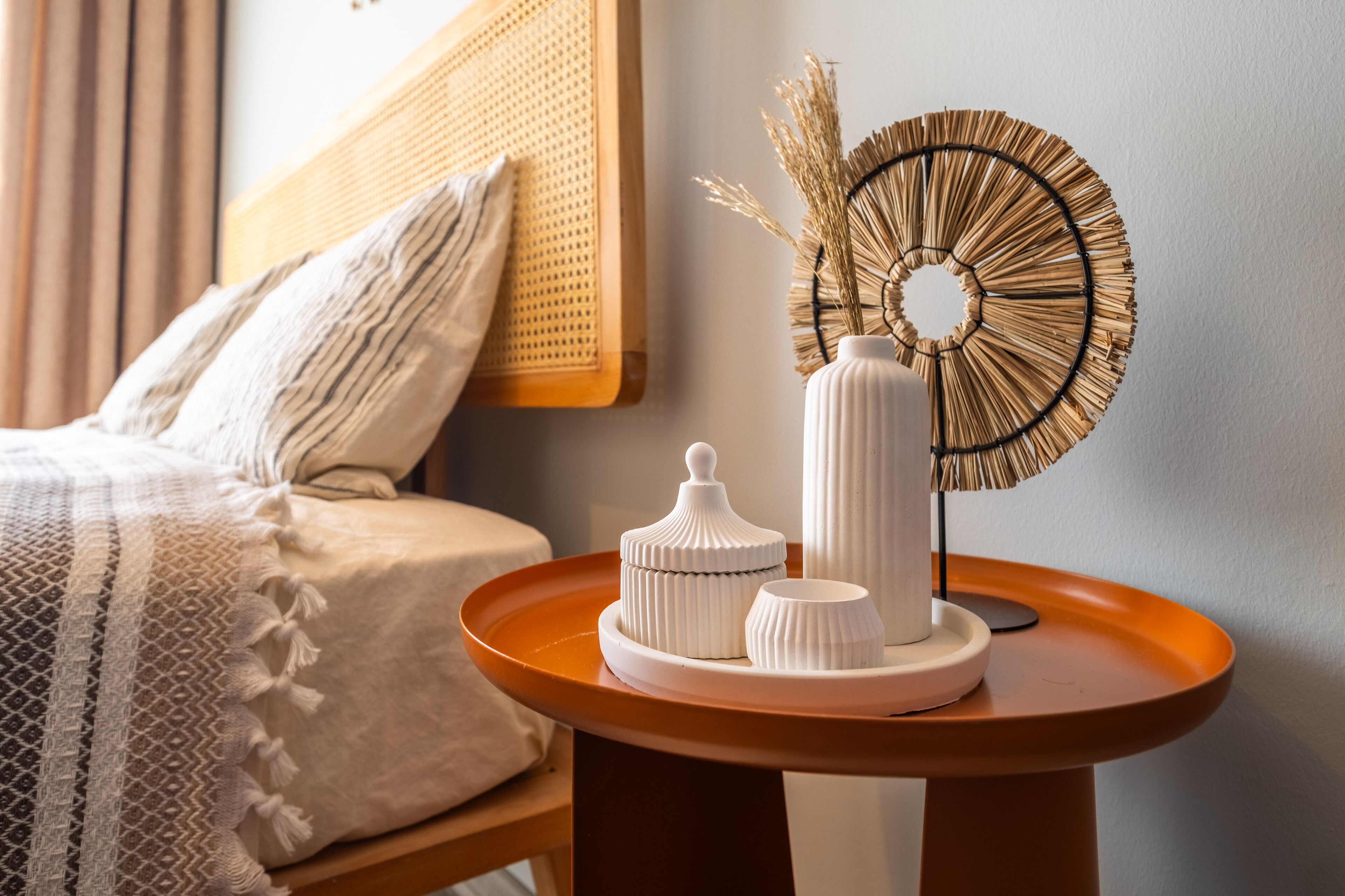 Ein ordentlich eingerichtetes Schlafzimmer mit Bett, Nachttisch und Dekorationselementen, darunter eine Vase und ein Wandbild.
