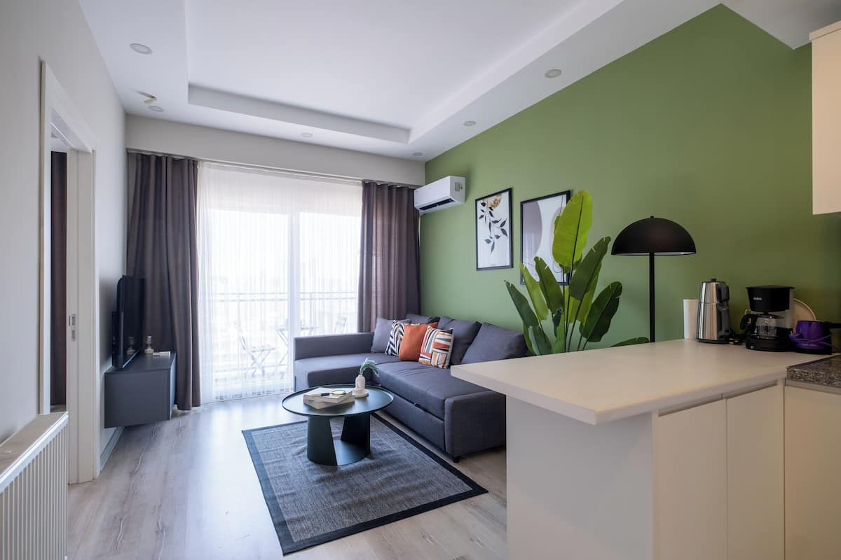 A modern living room with a grey sofa, a coffee table, and a large plant.