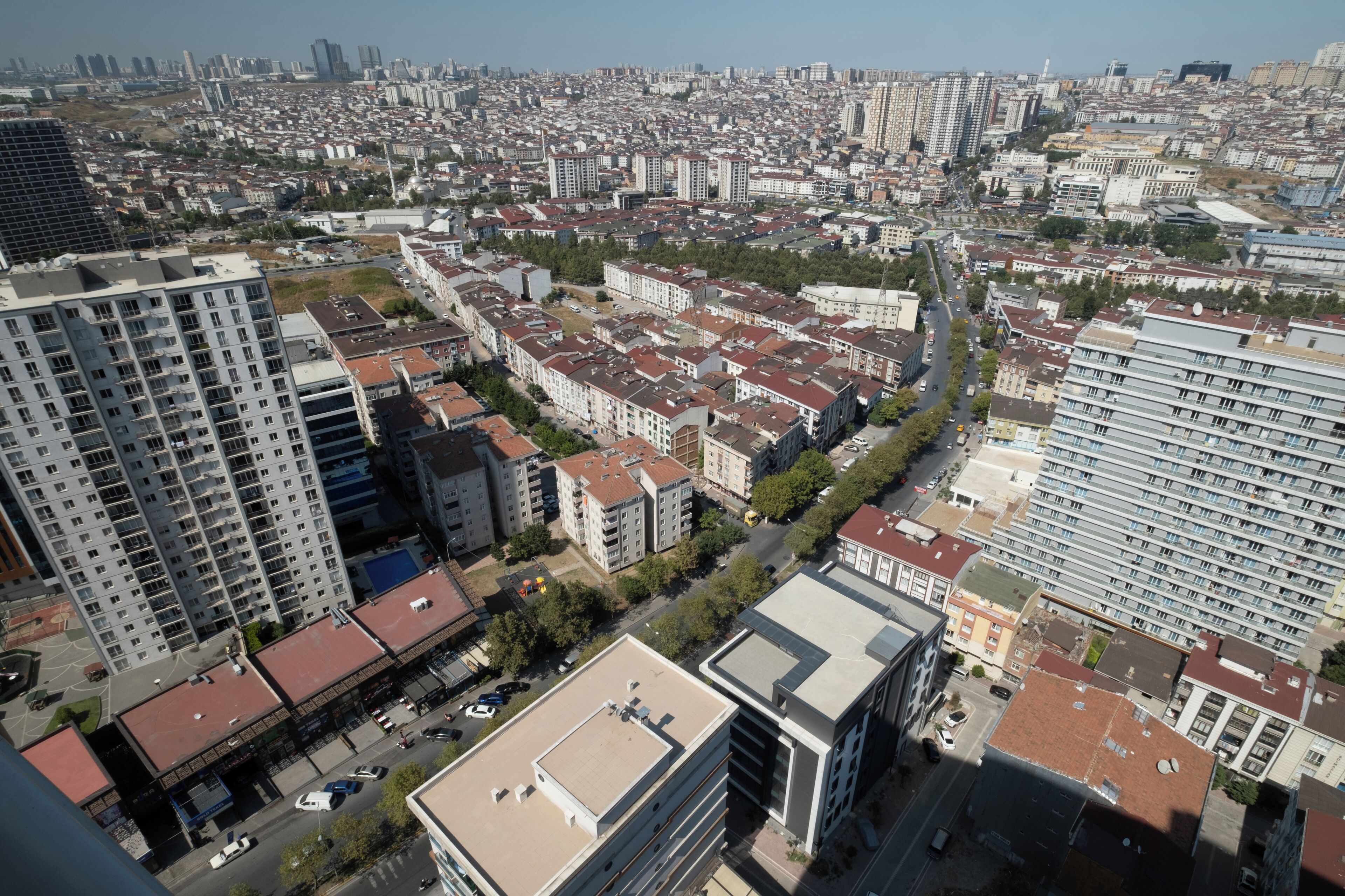 Un grattacielo con numerosi piani e un tetto piatto, circondato da altri edifici e una strada.