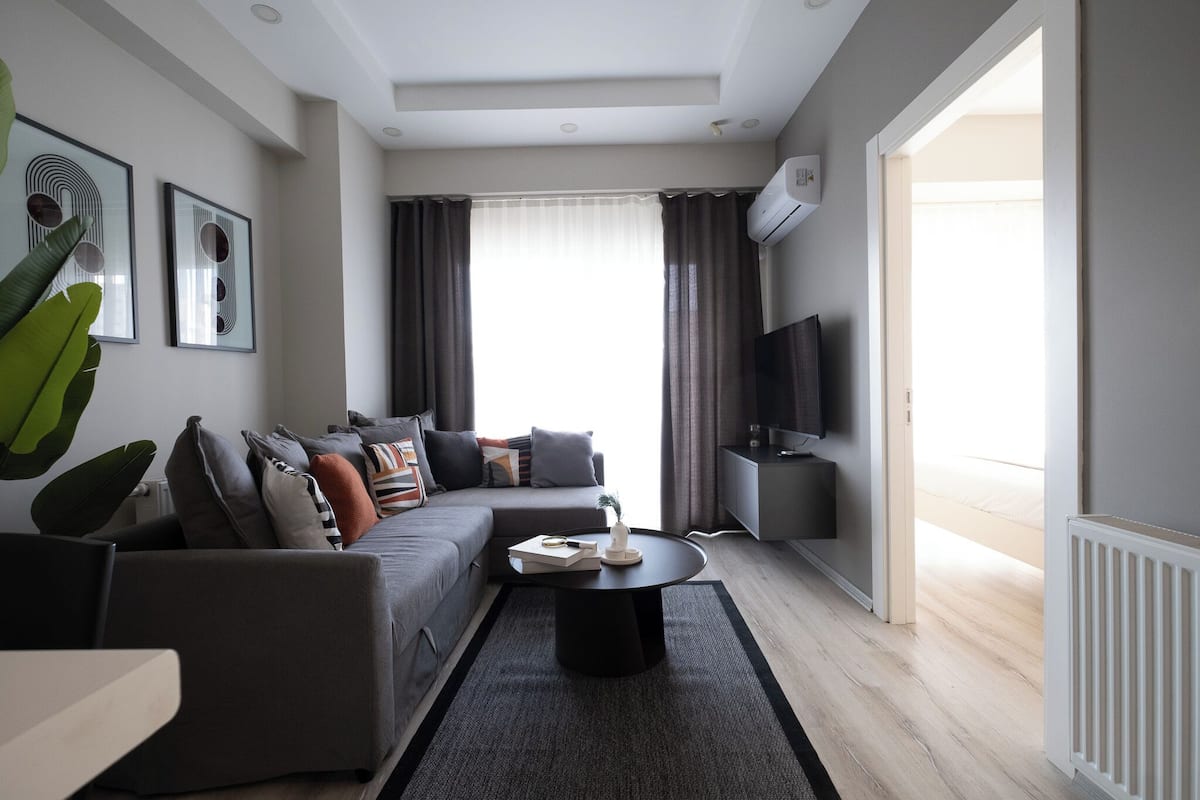 A modern living room with a grey sofa, a coffee table, and a flat-screen TV.