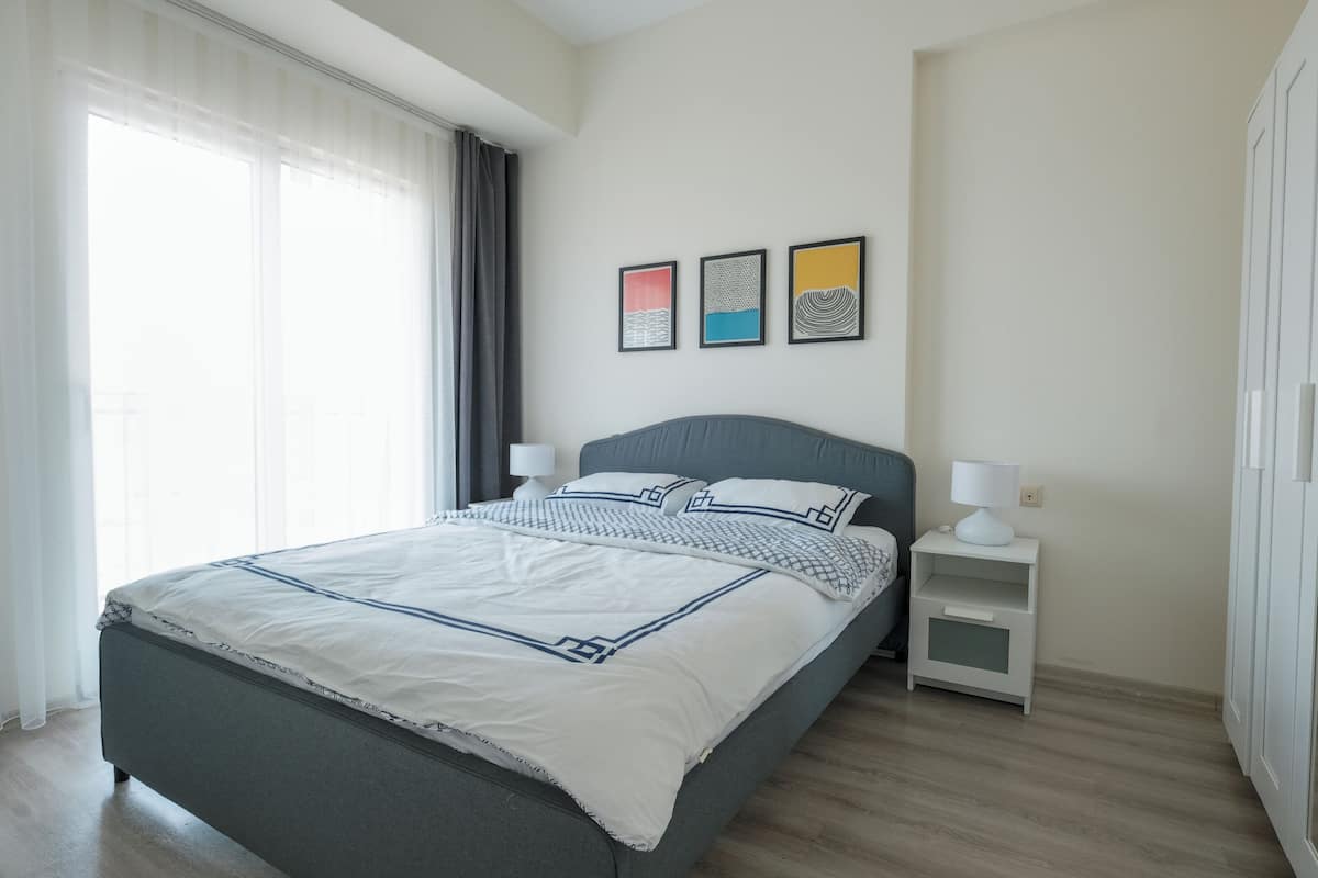 A modern bedroom with a bed, bedside tables, and artwork on the wall.