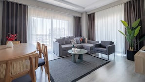 Una sala de estar moderna con un sofá gris, una mesa de centro redonda y una zona de comedor con una mesa y sillas de madera.