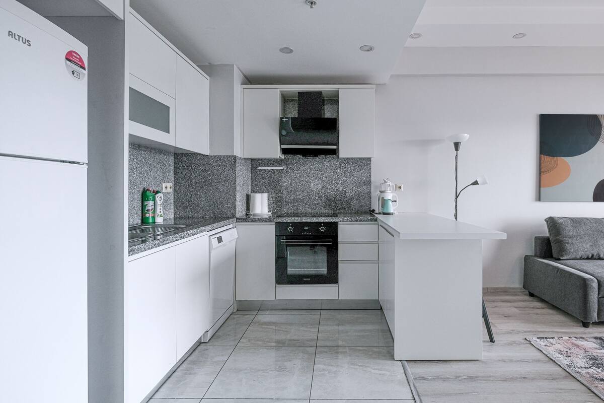 A modern kitchen with a dishwasher, oven, and granite countertops.