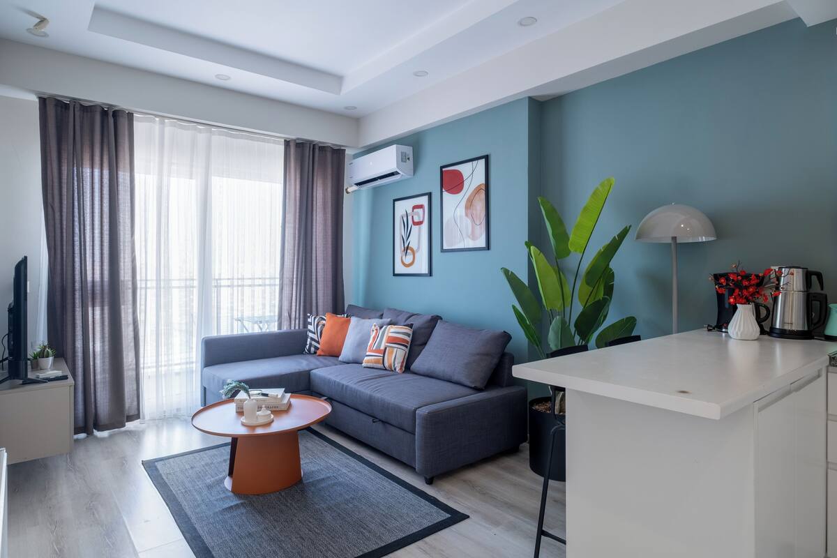 A modern living room with a grey sofa, a round coffee table, and a white kitchen island.