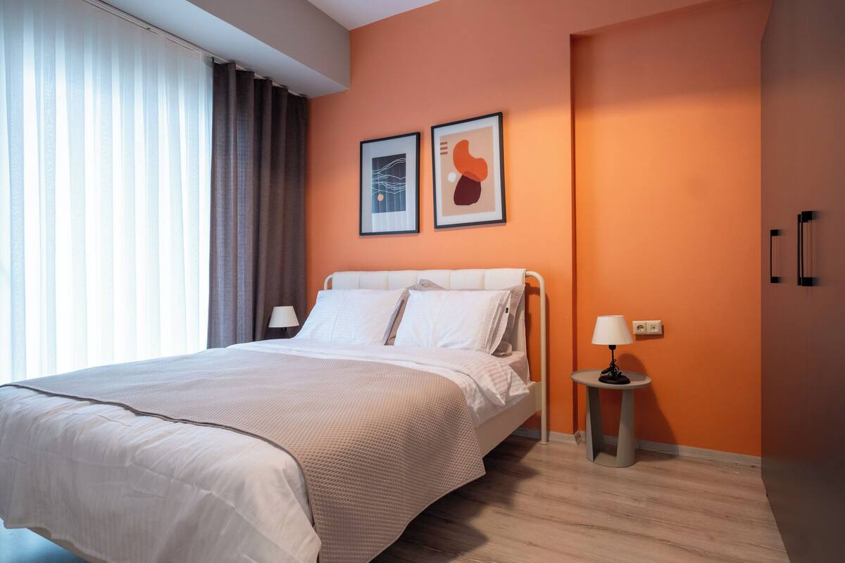 A hotel room with a bed, a nightstand, a lamp, and two framed pictures on the wall.