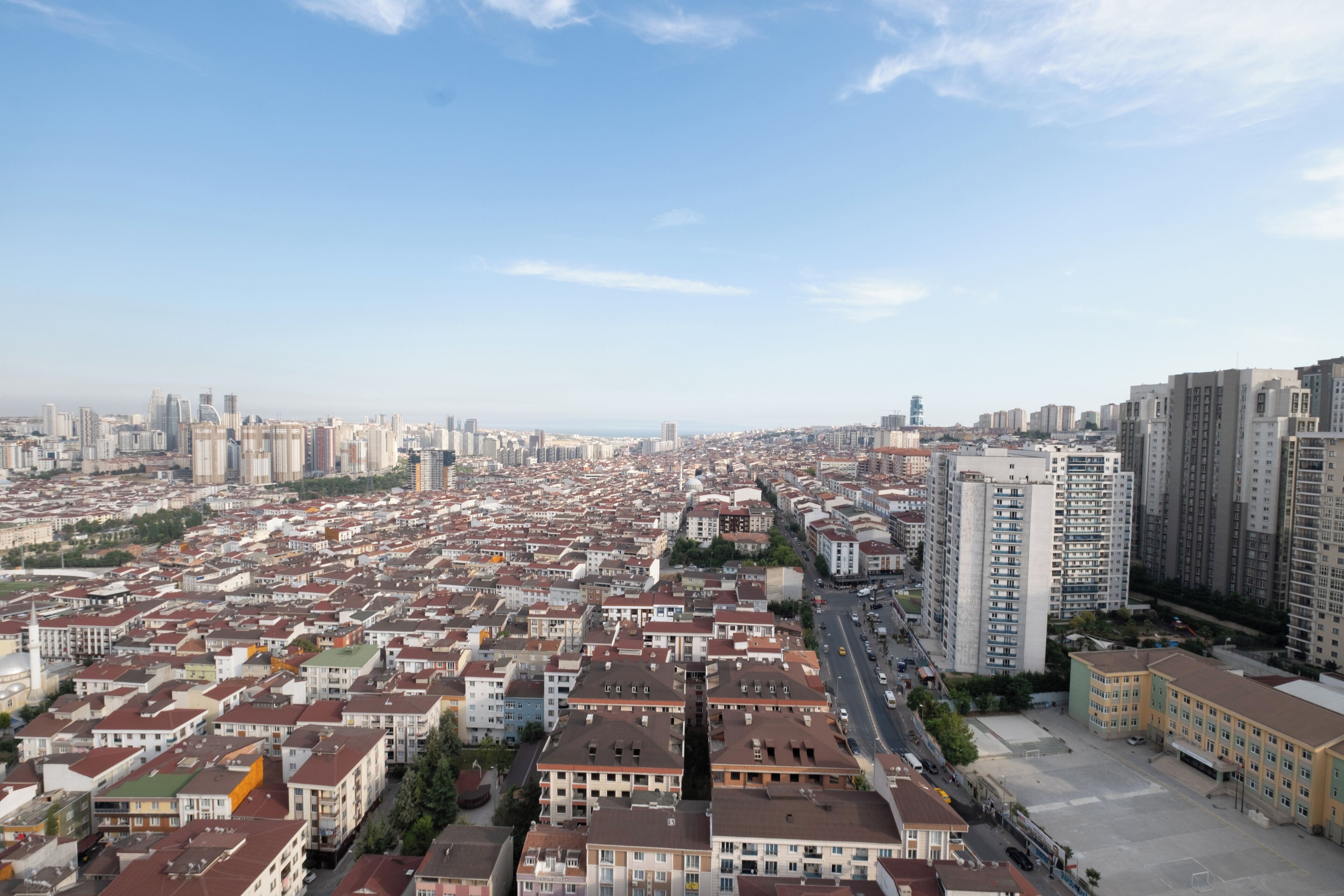 A cityscape with a mix of high-rise and low-rise buildings, a clear sky, and a wide street in the foreground.