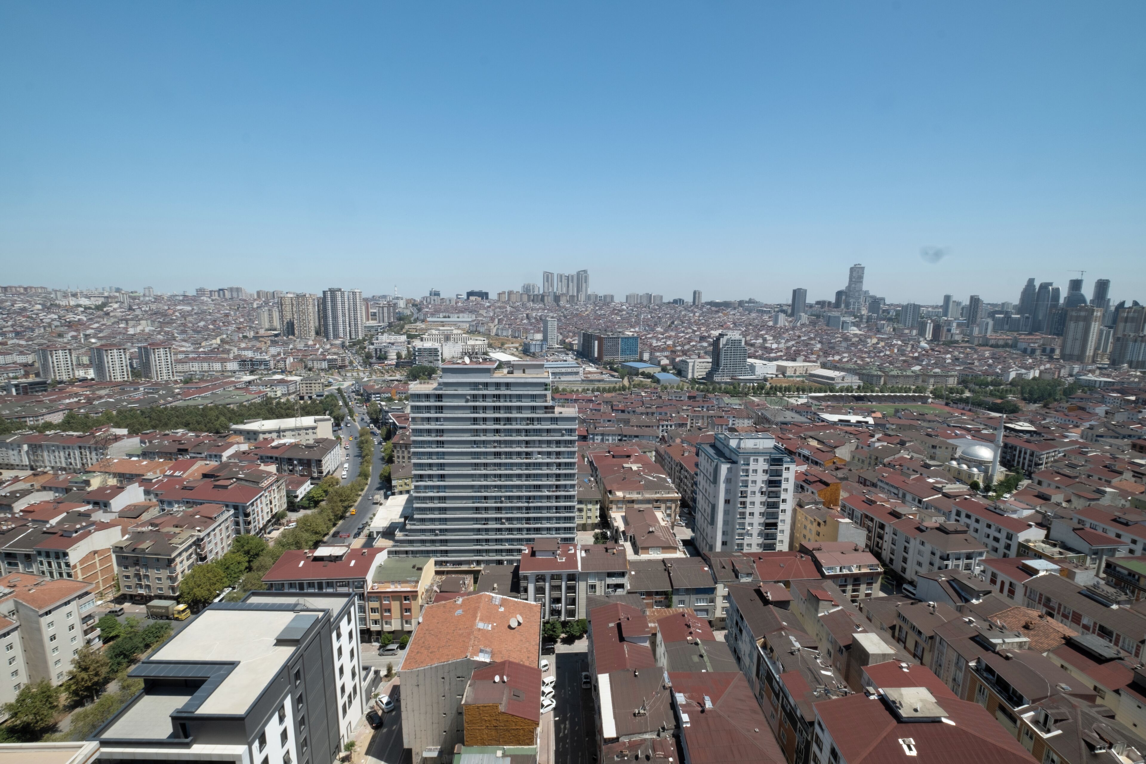A cityscape with a mix of high-rise and mid-rise buildings, a clear sky, and a dense urban layout.