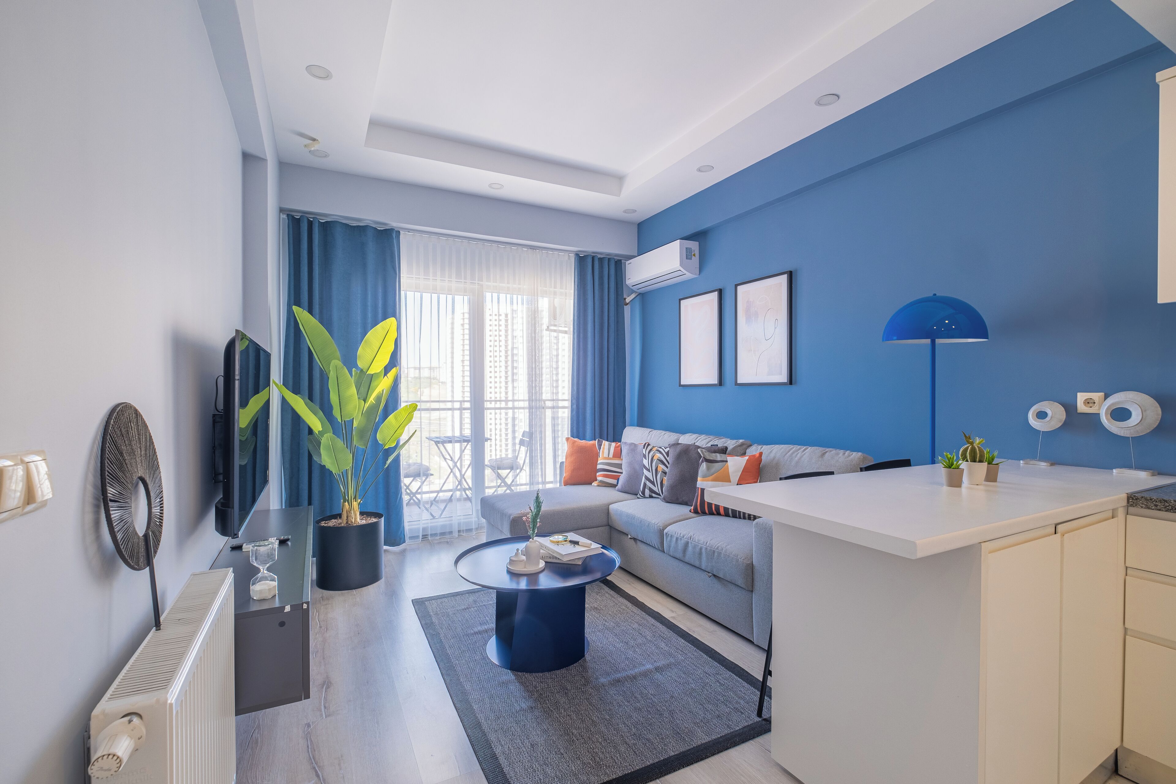 A modern living room with a sofa, coffee table, and a small kitchen area.