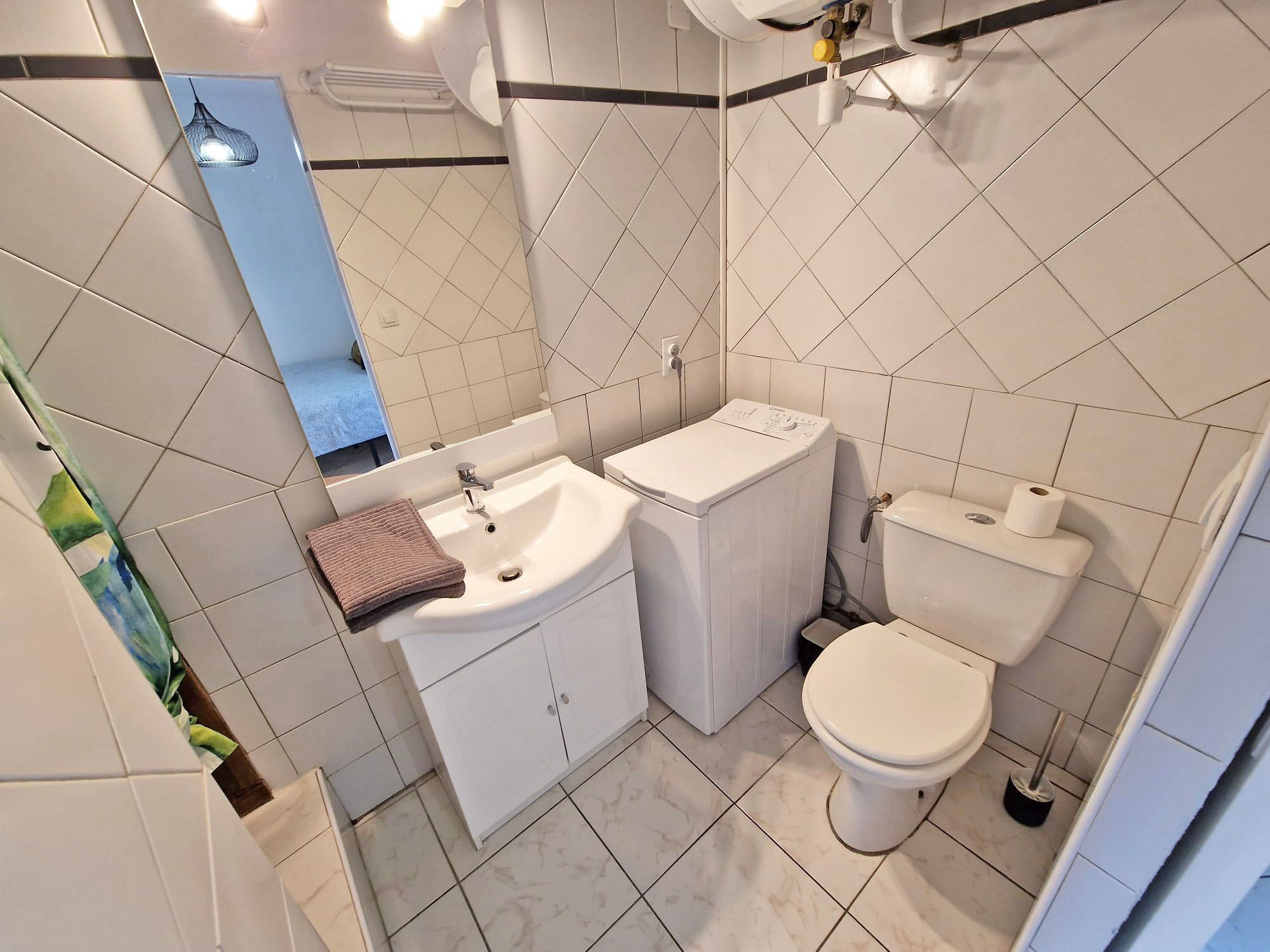 A bathroom with a sink, toilet, and washing machine.