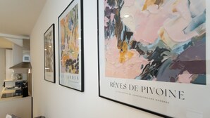 Moderni sisustus, jossa on harmaa sohva, kehystetty taideteos ja taustalla keittiötila.
