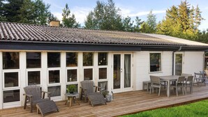 A house with a wooden deck, multiple windows, and outdoor furniture. - 4 bedroom awesome home in Sæby (Sæby)