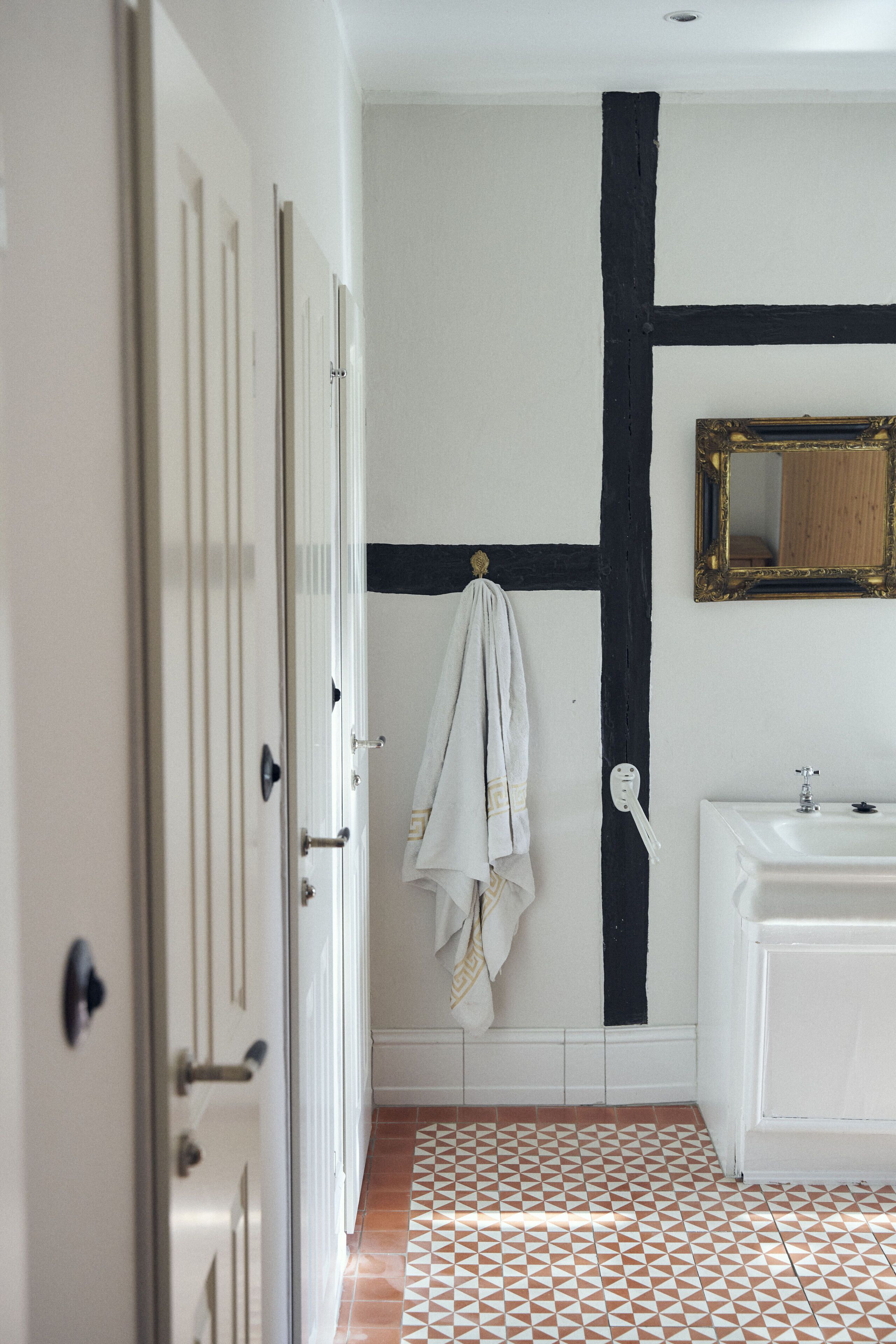 Une salle de bain avec un lavabo blanc, un miroir et un carrelage décoré.