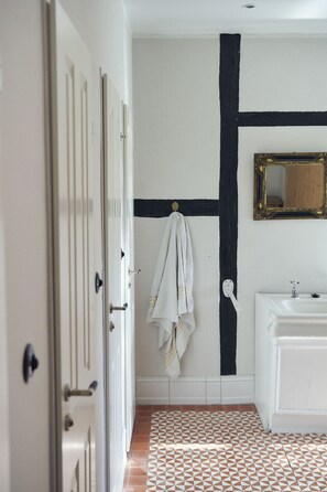 A bathroom with a white sink, a mirror, and a patterned floor. - Entire historic farmhouse with over 650 sqm & sea view (Fehmarn)