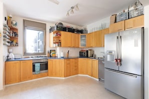A kitchen with wooden cabinets, a stainless steel refrigerator, and a window.