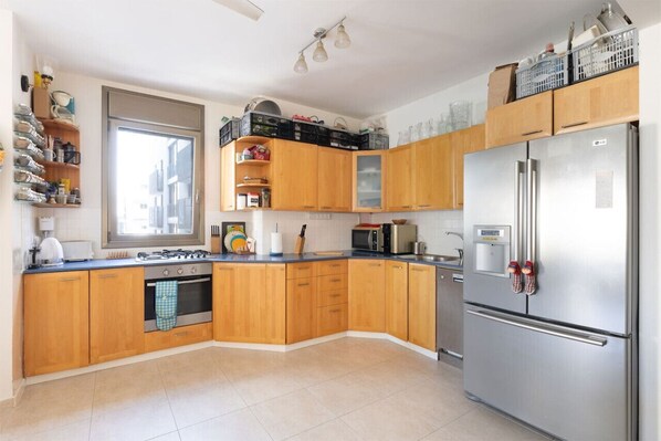 Una cucina con mobili in legno, un frigorifero in acciaio inossidabile e una finestra.