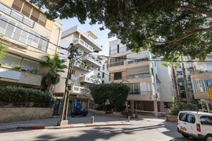 Un immeuble résidentiel à plusieurs étages, doté de balcons, d’une entrée sécurisée et d’un véhicule stationné.