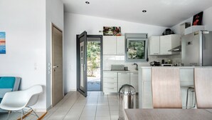Eine moderne Küche mit weißen Schränken, einem Edelstahlkühlschrank und Blick ins Freie.