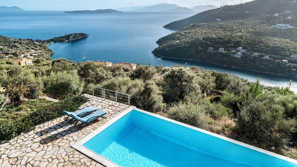 Ein Pool mit Stegterrasse mit Blick auf eine Küstenlandschaft mit Hügeln und einem Gewässer.