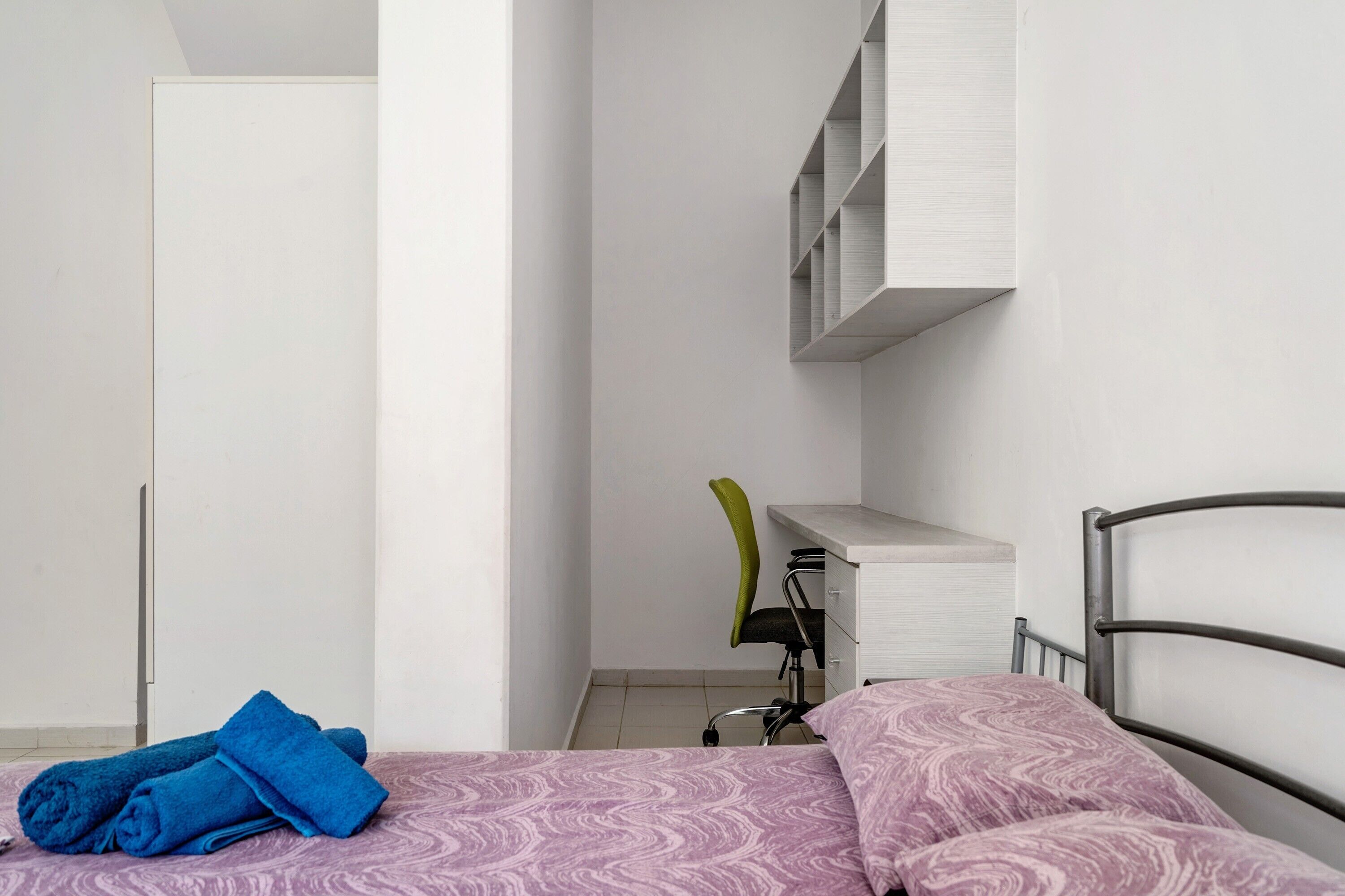A bedroom with a bed, a desk, and a chair.