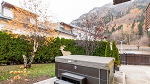 A patio with a barbecue grill, stone flooring, and a view of a mountain and residential buildings.