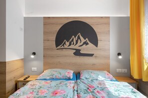 A bedroom with a bed, nightstands, and a wall-mounted light fixture. - Apartment 'Night and Day 4' with Mountain View, Balcony, and Wi-Fi (Predazzo)