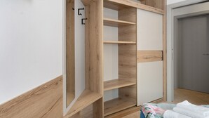 A room with a built-in wardrobe, a bed with a floral bedspread, and a grey door.