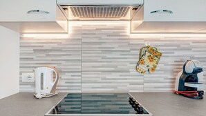 A modern kitchen with a built-in stove, a kettle, and a coffee maker. - Apartment 'Night and Day 8' with Mountain View, Balcony and Wi-Fi (Predazzo)