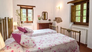 Un dormitorio con dos camas, un aparador, un espejo, una ventana y un radiador.