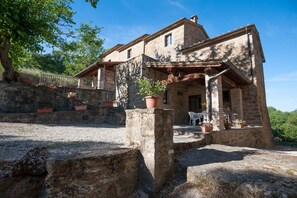A stone building with a balcony, potted plants, and a clear sky. - Farmhouse 'Pilari Appartamento Tabaccaia' with Mountain View, Shared Pool and Wi-Fi (Cortona)