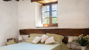 A bedroom with a wooden headboard, a window with open shutters, a bed with a green bedspread, and a potted plant. - Farmhouse "Pilari Appartamento Stalla" with Shared Pool, Private Terrace & Wi-Fi (Cortona)