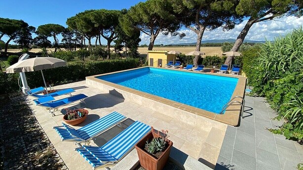Une piscine rectangulaire à l’eau bleue, entourée de chaises longues et de parasols.