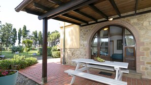 Un bâtiment en pierre avec un banc en bois et un patio couvert.