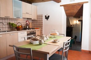 Eine Küche mit Holzausstattung, einer gefliesten Spritzschutzwand, einem Esstisch mit Stühlen und einem Teeservice.