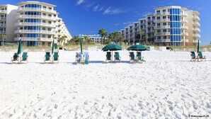 Un hôtel situé en bord de mer, doté de nombreux balcons, de chaises de plage et de parasols.