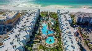 A resort with multiple buildings, a central swimming pool, and a beach.