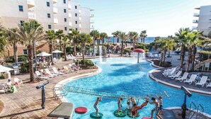 A pool area with lounge chairs and palm trees, surrounded by buildings. - Million$$ Panoramic Views from Wrap-Around Balcony! Free Beach Service! (Fort Walton Beach)
