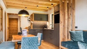 Una cocina acogedora con armarios de madera, horno empotrado y comedor con mesa y sillas.