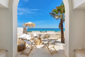 A sunlit outdoor seating area with lounge chairs, a thatched umbrella, and a view of the sea. - 2938 Palma Residence- Appartamento Zephyrus by Barbarhouse (Melendugno)