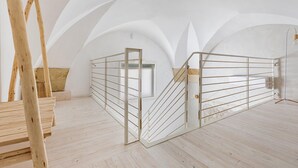 A spacious attic room with high ceilings, a wooden ladder, and a metal railing staircase.