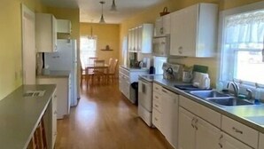 A kitchen with white cabinets, a wooden floor, and pendant lighting. - The Yellow House-Three bedroom within walking distance of Lake Michigan. (Ludington)