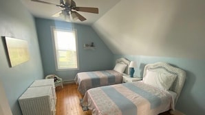 A bedroom with two beds, a ceiling fan, a window, and a small desk. - The Yellow House-Three bedroom within walking distance of Lake Michigan. (Ludington)