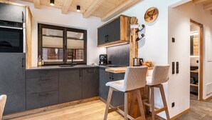 A modern kitchen with dark cabinets, a wooden ceiling, and a bar area with stools. - Mountain Chalet "Blosegghof Himmelblick" with Mountain View & New Whirlpool (Ratschings)