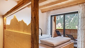 A wooden bed with a mountain mural, a window with a mountain view, and a balcony with chairs. - Mountain Chalet "Blosegghof Himmelblick" with Mountain View & New Whirlpool (Ratschings)