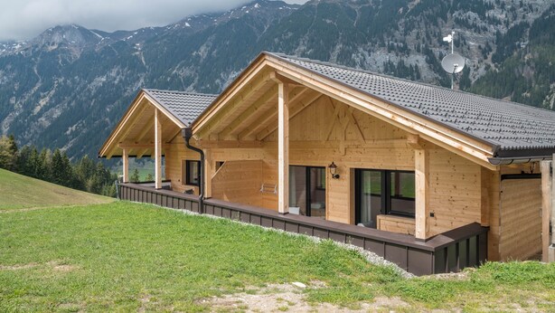 Eine Holzhütte mit geneigtem Dach, großen Fenstern und einem Balkon.